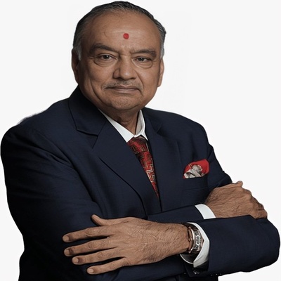 Portrait of Rajnikant S. Ajmera, Chairman and Managing Director of Ajmera Realty & Infra India Limited, standing with arms folded in a navy suit